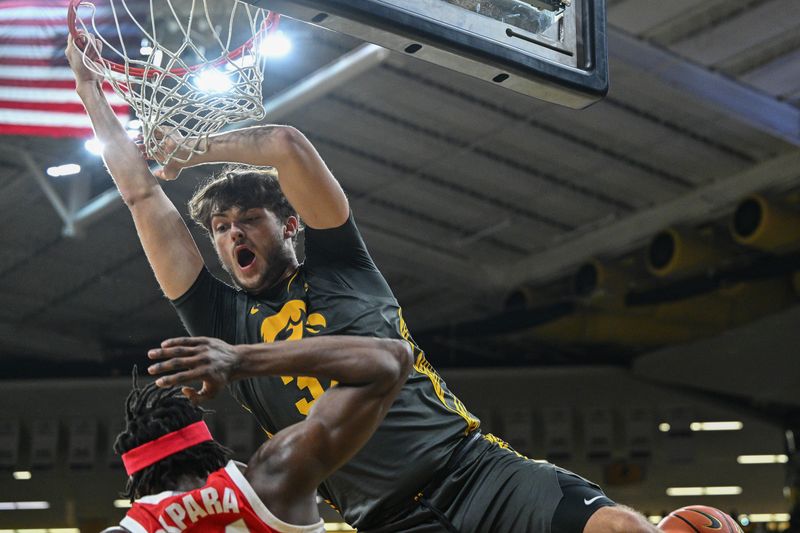 Feb 2, 2024; Iowa City, Iowa, USA; Iowa Hawkeyes forward Owen Freeman (32) completes a slam dunk over Ohio State Buckeyes center Felix Okpara (34) during the second half at Carver-Hawkeye Arena. Mandatory Credit: Jeffrey Becker-USA TODAY Sports