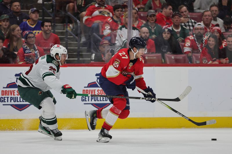 Oct 22, 2024; Sunrise, Florida, USA; Florida Panthers center Eetu Luostarinen (27) moves the puck ahead of Minnesota Wild defenseman Jonas Brodin (25) during the second period at Amerant Bank Arena. Mandatory Credit: Sam Navarro-Imagn Images