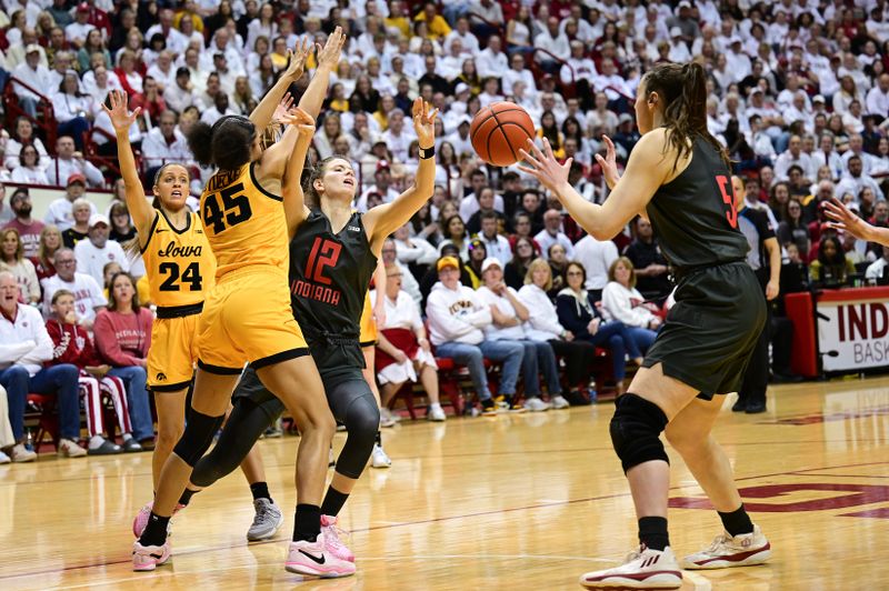 Feb 22, 2024; Bloomington, Indiana, USA; Iowa Hawkeyes forward Hannah Stuelke (45) knocks the ball away from Indiana Hoosiers guard Yarden Garzon (12) right into the hands of forward Mackenzie Holmes (54) during the second half at Simon Skjodt Assembly Hall. Mandatory Credit: Marc Lebryk-USA TODAY Sports