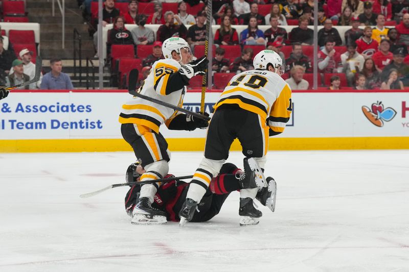 Mar 10, 2026; Raleigh, North Carolina, USA;  Pittsburgh Penguins center Tommy Novak (18) and Pittsburgh Penguins center Noel Acciari (55) check Carolina Hurricanes center Logan Stankoven (22) during the first period at Lenovo Center. Mandatory Credit: James Guillory-Imagn Images