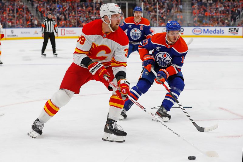 Oct 13, 2024; Edmonton, Alberta, CAN; Calgary Flames forward Antony Mantha (39) tries to carry the puck around Edmonton Oilers forward Mattias Janmark (13) during the second period at Rogers Place. Mandatory Credit: Perry Nelson-Imagn Images