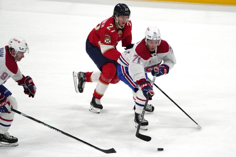 Dec 30, 2023; Sunrise, Florida, USA;  Montreal Canadiens center Jake Evans (71) brings the puck up the ice as Florida Panthers center Eetu Luostarinen (27) follows on the play during the third period at Amerant Bank Arena. Mandatory Credit: Jim Rassol-USA TODAY Sports