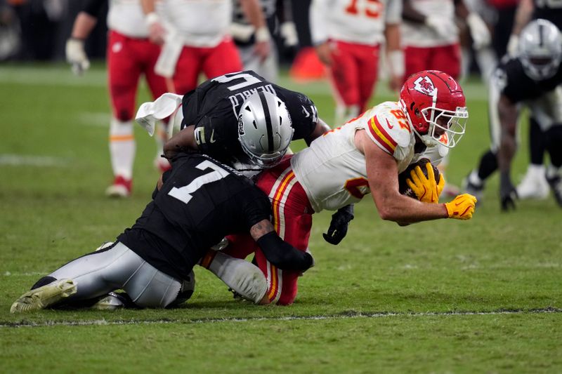 Kansas City Chiefs tight end Travis Kelce (87) is stopped by Las Vegas Raiders linebacker Divine Deablo (5) and safety Tre'von Moehrig (7) during the second half of an NFL football game Sunday, Oct. 27, 2024, in Las Vegas. (AP Photo/John Locher)