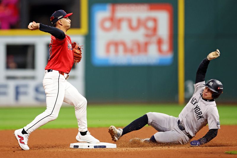 Oct 19, 2024; Cleveland, Ohio, USA; Cleveland Guardians second base Andrés Giménez (0) turns a double play over New York Yankees shortstop Anthony Volpe (11) during the fifth inning during game five of the ALCS for the 2024 MLB playoffs at Progressive Field. Mandatory Credit: Scott Galvin-Imagn Images