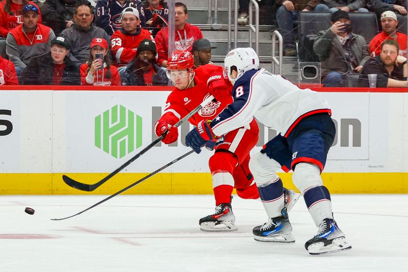 Mar 19, 2024; Detroit, Michigan, USA; Detroit Red Wings left wing Lucas Raymond (23) shoots the puck under pressure from Columbus Blue Jackets defenseman Zach Werenski (8) during the third period of the game at Little Caesars Arena. Mandatory Credit: Brian Bradshaw Sevald-USA TODAY Sports