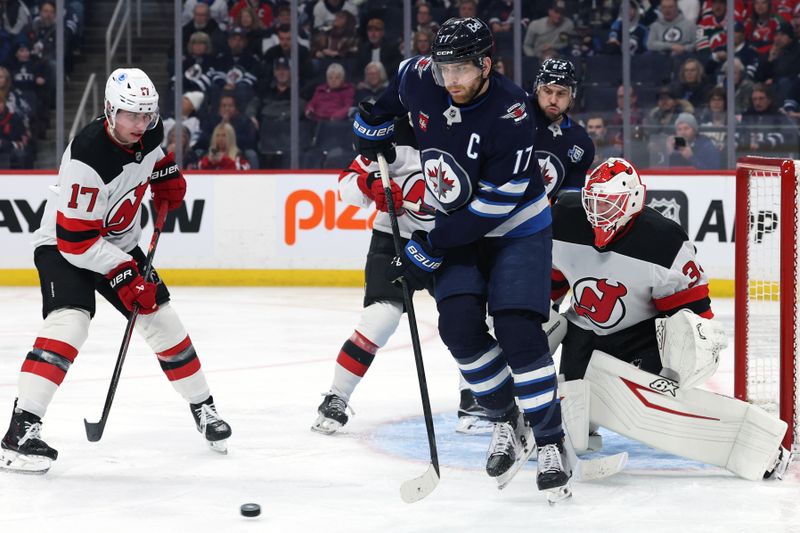 Jan 11, 2026; Winnipeg, Manitoba, CAN; Winnipeg Jets center Adam Lowry (17) eyes an incoming shot on New Jersey Devils goaltender Jake Allen (34) in the second period at Canada Life Centre. Mandatory Credit: James Carey Lauder-Imagn Images