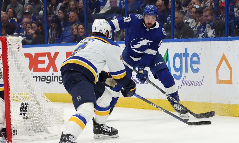 Dec 19, 2023; Tampa, Florida, USA; Tampa Bay Lightning left wing Nicholas Paul (20) passes the puck as St. Louis Blues defenseman Nick Leddy (4) defends during the first period at Amalie Arena. Mandatory Credit: Kim Klement Neitzel-USA TODAY Sports