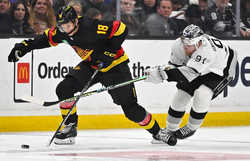 Apr 10, 2023; Los Angeles, California, USA;  Vancouver Canucks center Jack Studnicka (18) and Los Angeles Kings right wing Carl Grundstrom (91) battle for the puck in the first period at Crypto.com Arena. Mandatory Credit: Jayne Kamin-Oncea-USA TODAY Sports