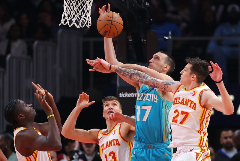 ATLANTA, GEORGIA - MARCH 23:  Aleksej Pokusevski #17 of the Charlotte Hornets grabs a rebound against Vit Krejci #27, Bogdan Bogdanovic #13 and Clint Capela #15 of the Atlanta Hawks during the second quarter at State Farm Arena on March 23, 2024 in Atlanta, Georgia.  NOTE TO USER: User expressly acknowledges and agrees that, by downloading and/or using this photograph, user is consenting to the terms and conditions of the Getty Images License Agreement.  (Photo by Kevin C. Cox/Getty Images)