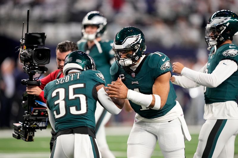 Philadelphia Eagles' Boston Scott (35) and Jalen Hurts, center, greet each other on the field during warmups before an NFL football game against the Dallas Cowboys in Arlington, Texas, Sunday, Dec. 10, 2023. (AP Photo/Tony Gutierrez)