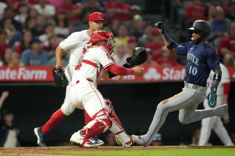 Aug 31, 2024; Anaheim, California, USA; Seattle Mariners center fielder Victor Robles (10) slides into home plate to beat a throw to Los Angeles Angels catcher Logan O'Hoppe (14) to score in the fourth inning at Angel Stadium. Mandatory Credit: Kirby Lee-USA TODAY Sports