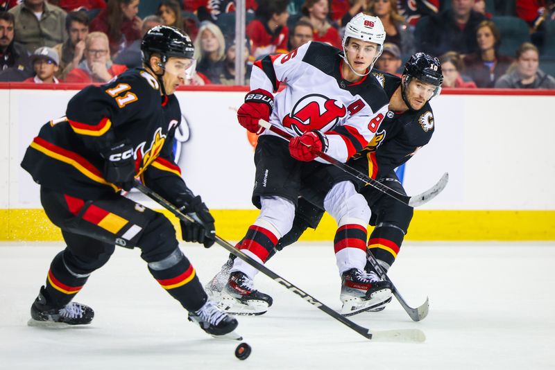 Dec 9, 2023; Calgary, Alberta, CAN; New Jersey Devils center Jack Hughes (86) passes the puck against the Calgary Flames during the third period at Scotiabank Saddledome. Mandatory Credit: Sergei Belski-USA TODAY Sports