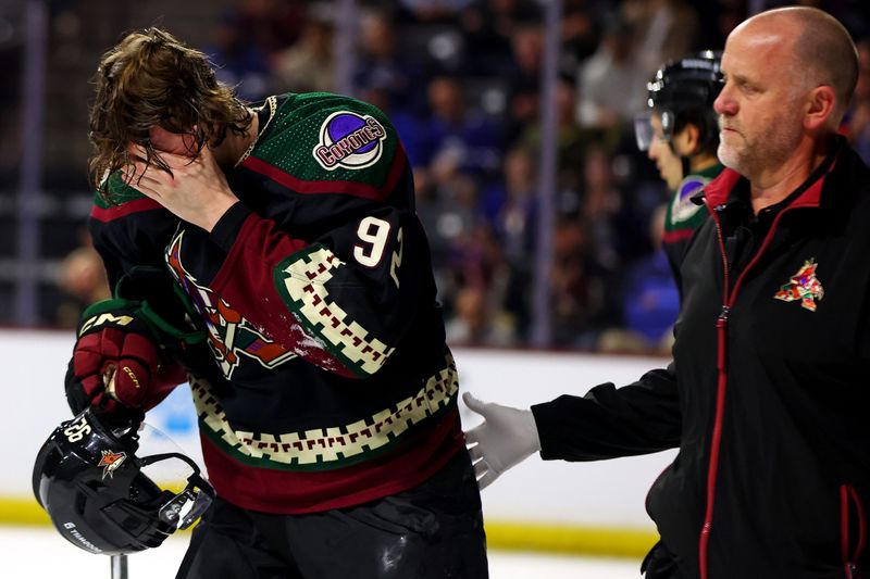 Feb 21, 2024; Tempe, Arizona, USA; Arizona Coyotes center Logan Cooley (92) is helped off the ice after an injury during the second period against the Toronto Maple Leafs at Mullett Arena. Mandatory Credit: Mark J. Rebilas-USA TODAY Sports