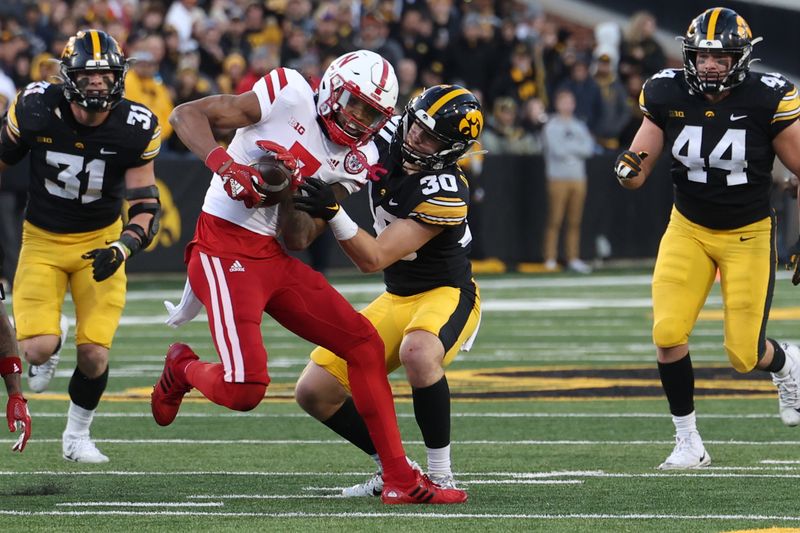 Nov 25, 2022; Iowa City, Iowa, USA; Nebraska Cornhuskers wide receiver Marcus Washington (7) is tackled by Iowa Hawkeyes defensive back Quinn Schulte (30) at Kinnick Stadium. Mandatory Credit: Reese Strickland-USA TODAY Sports