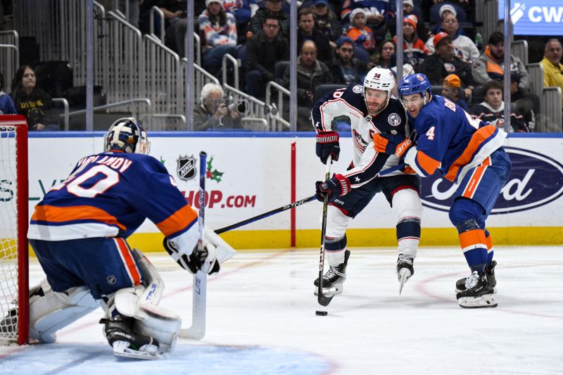 Dec 7, 2023; Elmont, New York, USA; Columbus Blue Jackets center Boone Jenner (38) skates with the puck against New York Islanders defenseman Samuel Bolduc (4) as New York Islanders goaltender Semyon Varlamov (40) tends net during the third period at UBS Arena. Mandatory Credit: John Jones-USA TODAY Sports