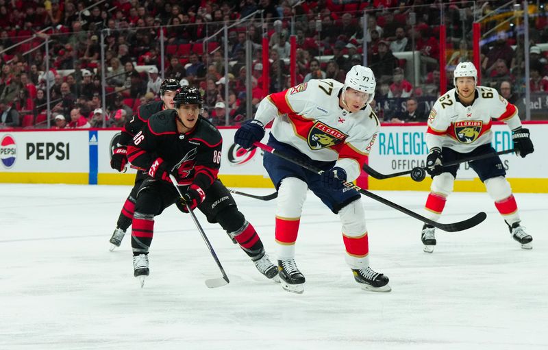 Mar 14, 2024; Raleigh, North Carolina, USA; Florida Panthers defenseman Niko Mikkola (77) and Carolina Hurricanes left wing Teuvo Teravainen (86) chase after the puck during the first period at PNC Arena. Mandatory Credit: James Guillory-USA TODAY Sports