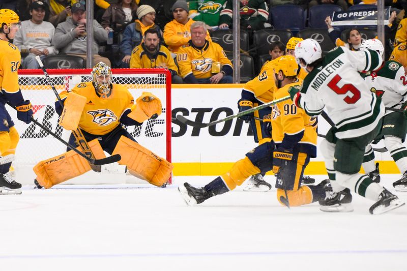 Jan 18, 2025; Nashville, Tennessee, USA;  Nashville Predators goaltender Juuse Saros (74) blocks the shot of Minnesota Wild defenseman Jake Middleton (5) during the third period at Bridgestone Arena. Mandatory Credit: Steve Roberts-Imagn Images