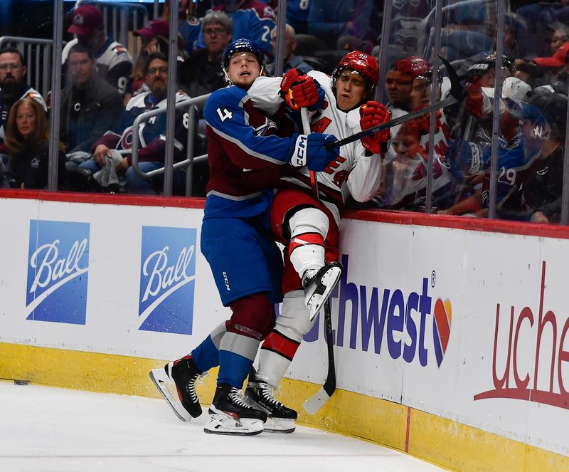 Oct 21, 2023; Denver, Colorado, USA; Colorado Avalanche defenseman Bowen Byram (4) pounds Carolina Hurricanes left wing Teuvo Teravainen (86) up against the boards in the first period at Ball Arena. Mandatory Credit: John Leyba-USA TODAY Sports