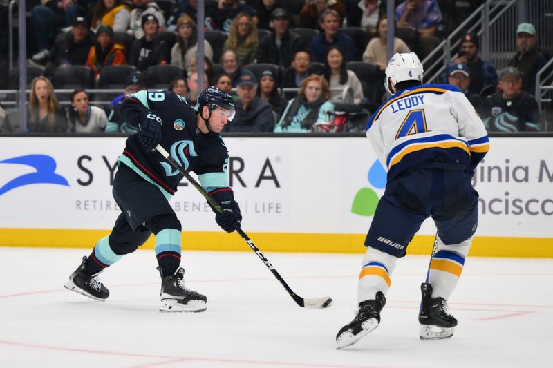 Jan 26, 2024; Seattle, Washington, USA; Seattle Kraken left wing Jared McCann (19) passes the puck while defended by St. Louis Blues defenseman Nick Leddy (4) during overtime at Climate Pledge Arena. Mandatory Credit: Steven Bisig-USA TODAY Sports