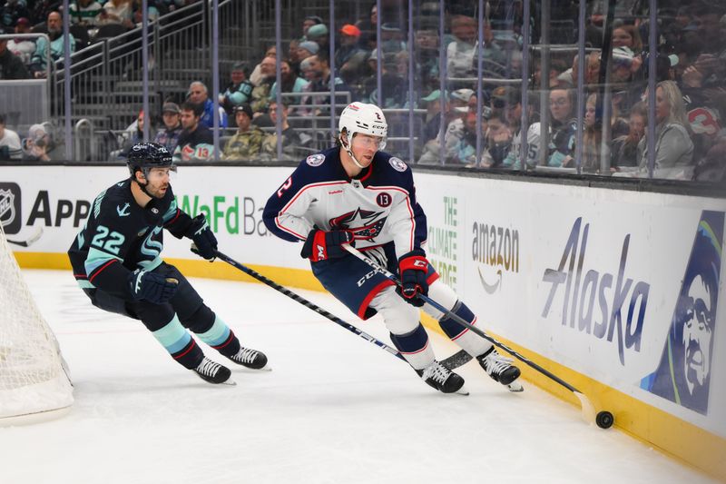 Nov 12, 2024; Seattle, Washington, USA; Columbus Blue Jackets defenseman Jake Christiansen (2) plays the puck while defended by Seattle Kraken right wing Oliver Bjorkstrand (22) during the third period at Climate Pledge Arena. Mandatory Credit: Steven Bisig-Imagn Images