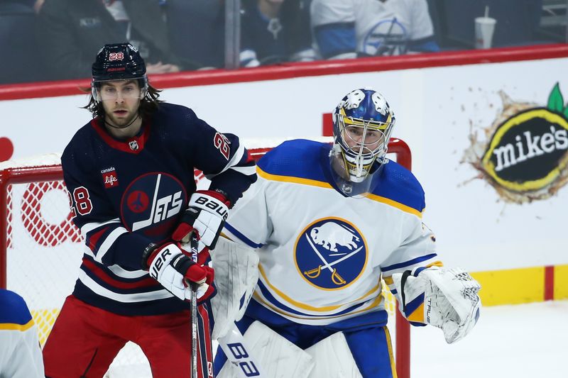 Jan 26, 2023; Winnipeg, Manitoba, CAN;  Buffalo Sabres goalie Eric Comrie (31) and Winnipeg Jets forward Kevin Stenlund (28) look for the puck during the third period at Canada Life Centre. Mandatory Credit: Terrence Lee-USA TODAY Sports