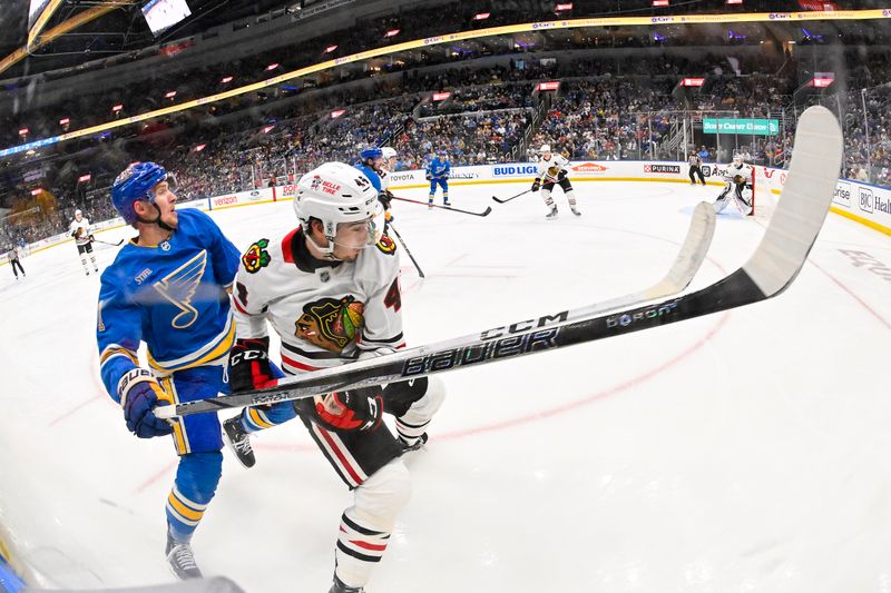 Mar 22, 2025; St. Louis, Missouri, USA;  St. Louis Blues center Dylan Holloway (81) skates against Chicago Blackhawks defenseman Wyatt Kaiser (44) during the second period at Enterprise Center. Mandatory Credit: Jeff Curry-Imagn Images