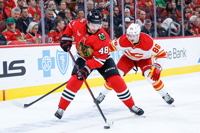 Nov 18, 2025; Chicago, Illinois, USA; Chicago Blackhawks defenseman Matt Grzelcyk (48) defends against Calgary Flames left wing Joel Farabee (86) during the first period at United Center. Mandatory Credit: Kamil Krzaczynski-Imagn Images