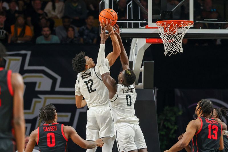 Jan 25, 2023; Orlando, Florida, USA; UCF Knights guard Ithiel Horton (12) and forward Lahat Thioune (0) jump for the rebound during the second half at Addition Financial Arena. Mandatory Credit: Mike Watters-USA TODAY Sports