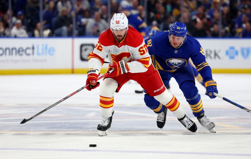 Nov 9, 2024; Buffalo, New York, USA;  Calgary Flames defenseman MacKenzie Weegar (52) and Buffalo Sabres center Sam Lafferty (81) skate for a loose puck during the second period at KeyBank Center. Mandatory Credit: Timothy T. Ludwig-Imagn Images