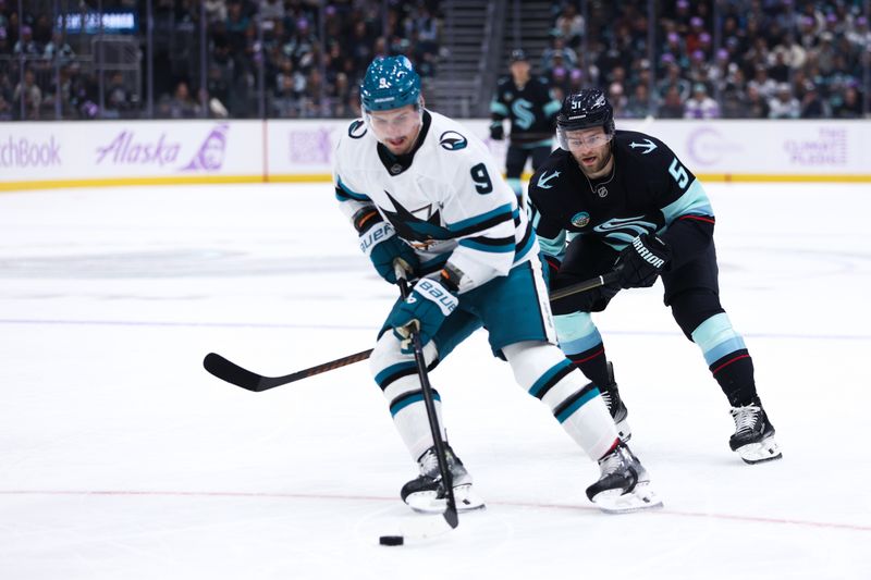 Nov 15, 2025; Seattle, Washington, USA; Seattle Kraken center Shane Wright (51) defends as San Jose Sharks defenseman Dmitry Orlov (9) controls the puck in the first period at Climate Pledge Arena. Mandatory Credit: Kevin Ng-Imagn Images
