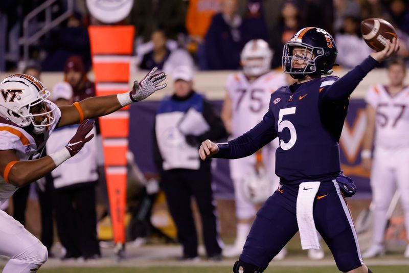 Nov 27, 2021; Charlottesville, Virginia, USA; DUPLICATE***Virginia Cavaliers quarterback Brennan Armstrong (5) passes the ball as Virginia Tech Hokies defensive lineman TyJuan Garbutt (45) defends during the fourth quarter at Scott Stadium. Mandatory Credit: Geoff Burke-USA TODAY Sports