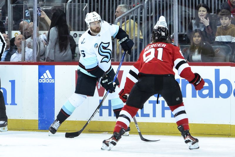 Feb 12, 2024; Newark, New Jersey, USA; Seattle Kraken defenseman Adam Larsson (6) skates with the puck as New Jersey Devils center Dawson Mercer (91) defends during the first period at Prudential Center. Mandatory Credit: John Jones-USA TODAY Sports