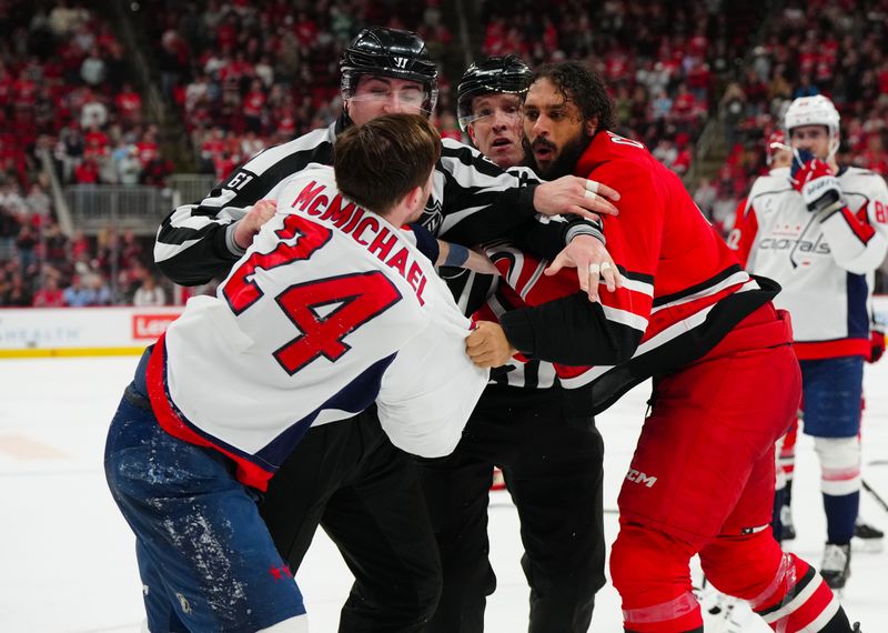 Apr 2, 2025; Raleigh, North Carolina, USA;  Carolina Hurricanes defenseman Jalen Chatfield (5) and Washington Capitals center Connor McMichael (24) fight during the third period at Lenovo Center. Mandatory Credit: James Guillory-Imagn Images