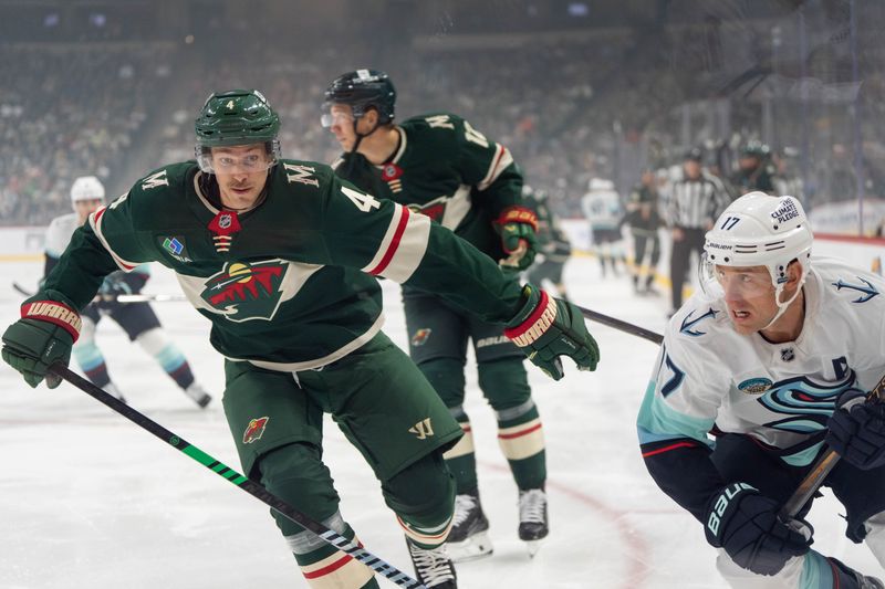 Oct 12, 2024; Saint Paul, Minnesota, USA; Minnesota Wild defenseman Jon Merrill (4) looks to check Seattle Kraken center Jaden Schwartz (17) in the corner in the first period at Xcel Energy Center. Mandatory Credit: Matt Blewett-Imagn Images