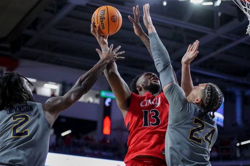 Mar 9, 2024; Cincinnati, Ohio, USA; Cincinnati Bearcats forward Jamille Reynolds (13) shoots against West Virginia Mountaineers guard Kobe Johnson (2) and forward Patrick Suemnick (24) in the first half at Fifth Third Arena. Mandatory Credit: Katie Stratman-USA TODAY Sports