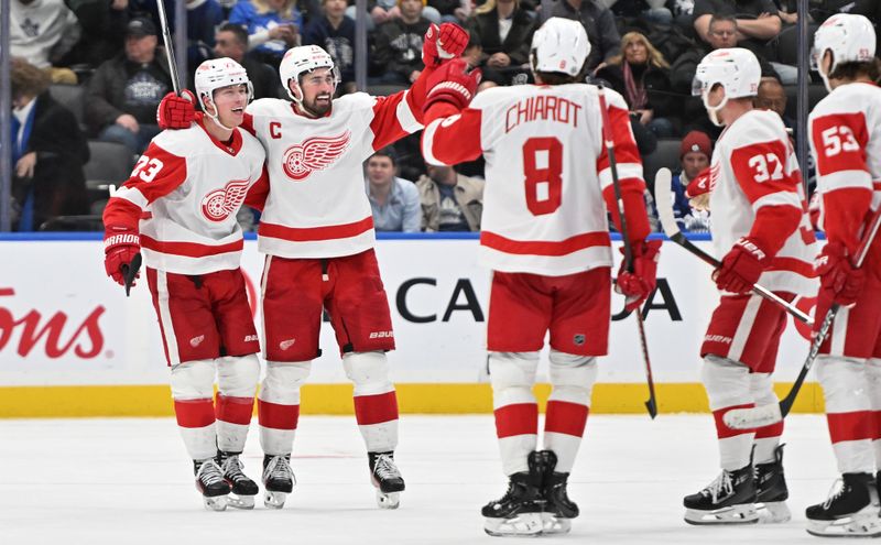 Jan 14, 2024; Toronto, Ontario, CAN;  Detroit Red Wings forward Lucas Raymond (23) celebrates with forward Dylan Larkin (71) and teammates after scoring against the Toronto Maple Leafs at Scotiabank Arena. Mandatory Credit: Dan Hamilton-USA TODAY Sports