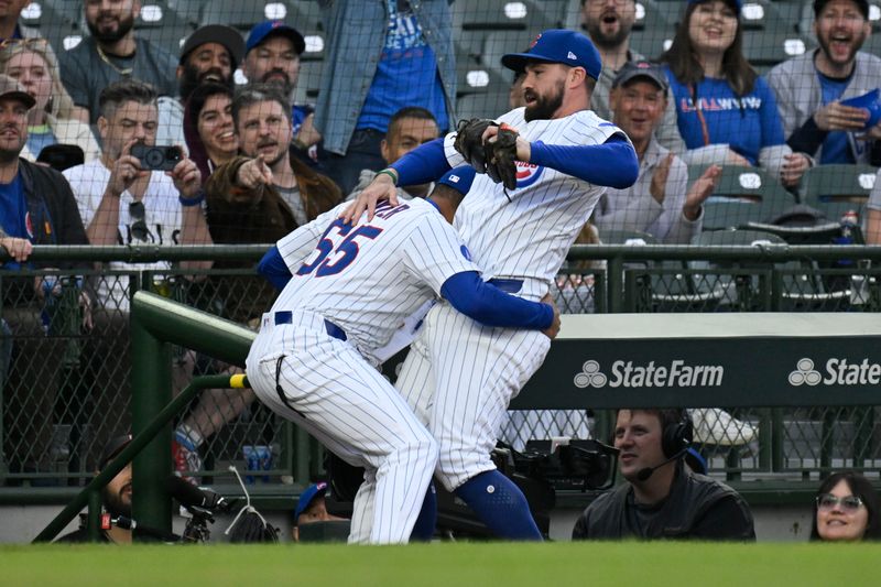 May 12, 2025; Chicago, Illinois, USA;  Chicago Cubs first base coach Jose Javier (65) stops  second baseman Jon Berti (5) from falling after he caught a fly ball in foul territory hit by Miami Marlins second base Ronny Simon (41) during the second inning at Wrigley Field. Mandatory Credit: Matt Marton-Imagn Images