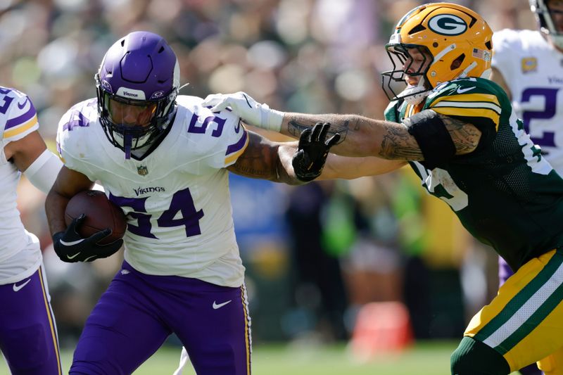 Minnesota Vikings linebacker Kamu Grugier-Hill (54) returns an interception past Green Bay Packers tight end Tucker Kraft, right, during the first half of an NFL football game Sunday, Sept. 29, 2024, in Green Bay, Wis. (AP Photo/Matt Ludtke)