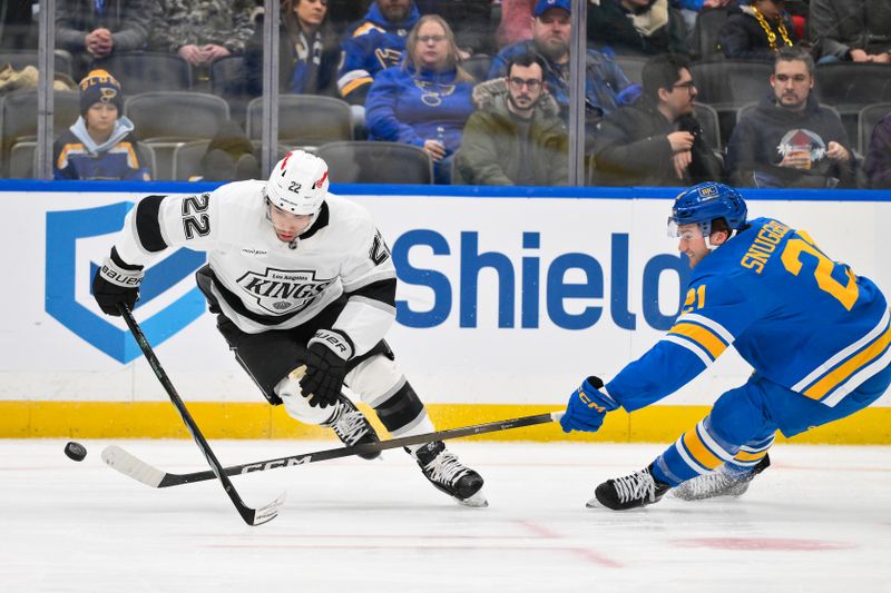 Jan 24, 2026; St. Louis, Missouri, USA; St. Louis Blues right wing Jimmy Snuggerud (21) pokes the puck away from Los Angeles Kings left wing Kevin Fiala (22) during the second period at Enterprise Center. Mandatory Credit: Jeff Curry-Imagn Images