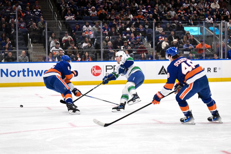 Dec 19, 2025; Elmont, New York, USA; Vancouver Canucks right wing Brock Boeser (6) passes the puck while defended by New York Islanders defenseman Ryan Pulock (6) during the first period at UBS Arena. Mandatory Credit: John Jones-Imagn Images