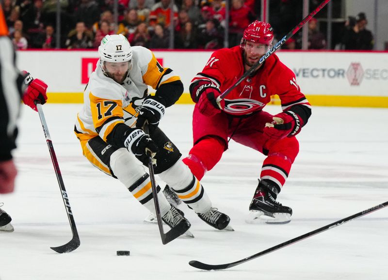 Jan 13, 2024; Raleigh, North Carolina, USA;  Pittsburgh Penguins right wing Bryan Rust (17) skates with the puck past Carolina Hurricanes center Jordan Staal (11) during the second period at PNC Arena. Mandatory Credit: James Guillory-USA TODAY Sports