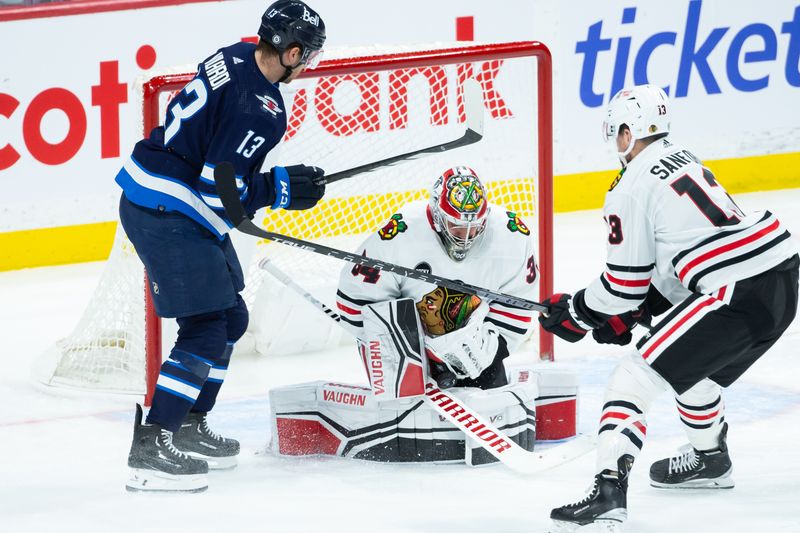 Jan 11, 2024; Winnipeg, Manitoba, CAN; Chicago Blackhawks goalie Petr Mrazek (34) makes a save as Winnipeg Jets forward Gabriel Vilardi (13) and Chicago Blackhawks forward Zachary Sanfird (13) look for a rebound during the third period at Canada Life Centre. Mandatory Credit: Terrence Lee-USA TODAY Sports