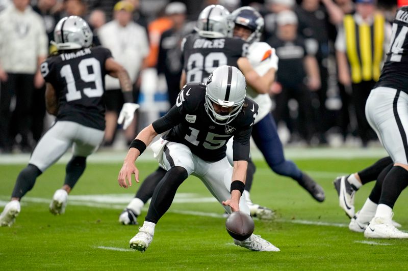 Las Vegas Raiders quarterback Gardner Minshew (15) bobbles the snap during the first half of an NFL football game against the Denver Broncos, Sunday, Nov. 24, 2024, in Las Vegas. (AP Photo/John Locher)