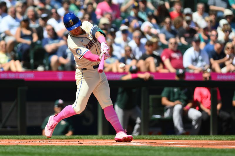 May 12, 2024; Seattle, Washington, USA; Seattle Mariners shortstop Dylan Moore (25) hits a single against the Oakland Athletics during the first inning at T-Mobile Park. Mandatory Credit: Steven Bisig-USA TODAY Sports