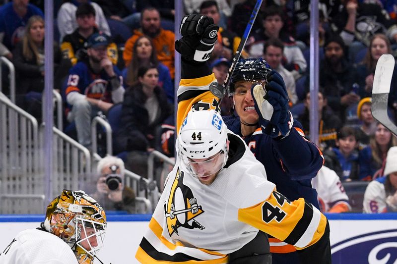 Dec 27, 2022; Elmont, New York, USA; New York Islanders left wing Anders Lee (27) attempts to batt the puck out of the air defended by Pittsburgh Penguins defenseman Jan Rutta (44) during the second period at UBS Arena. Mandatory Credit: Dennis Schneidler-USA TODAY Sports