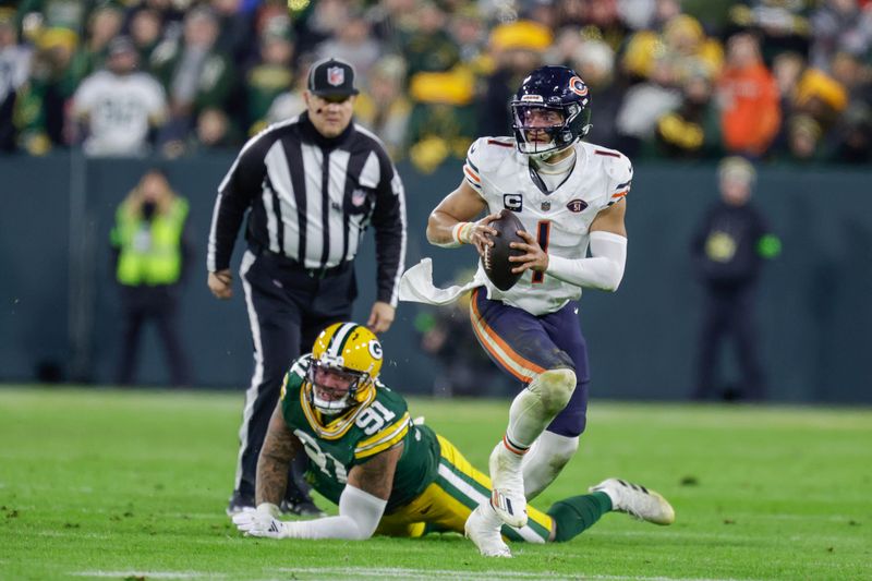 Chicago Bears quarterback Justin Fields (1) scrambles around Green Bay Packers linebacker Preston Smith (91) during an NFL football game between the Green Bay Packers and Chicago Bears Sunday, Jan. 7, 2024, in Green Bay, Wis. (AP Photo/Matt Ludtke)