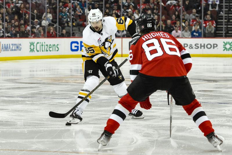 Apr 2, 2024; Newark, New Jersey, USA; Pittsburgh Penguins defenseman Erik Karlsson (65) skates with the puck while being defended by New Jersey Devils center Jack Hughes (86) during the third period at Prudential Center. Mandatory Credit: John Jones-USA TODAY Sports