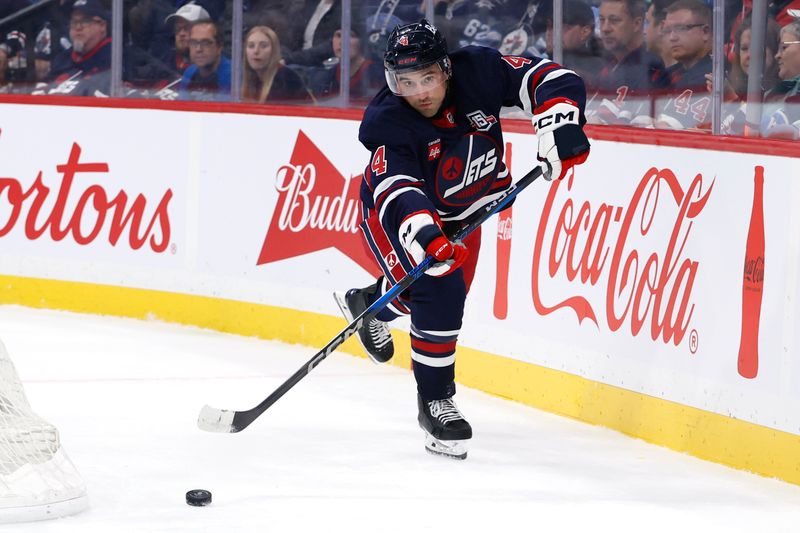 Oct 23, 2025; Winnipeg, Manitoba, CAN; Winnipeg Jets defenseman Neal Pionk (4) shoots the puck up the ice against the Seattle Kraken in the first period at Canada Life Centre. Mandatory Credit: James Carey Lauder-Imagn Images