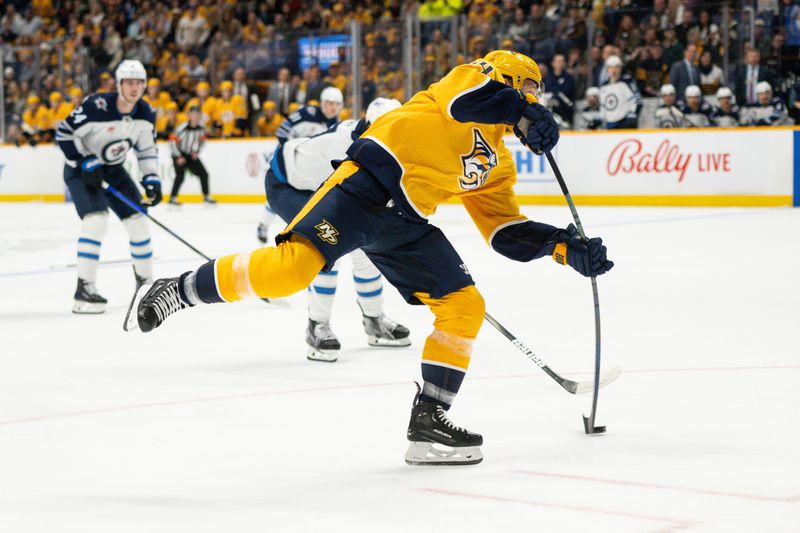 Nov 23, 2024; Nashville, Tennessee, USA;  Nashville Predators defenseman Alexandre Carrier (45) takes a shot against the Winnipeg Jets during the first period at Bridgestone Arena. Mandatory Credit: Steve Roberts-Imagn Images