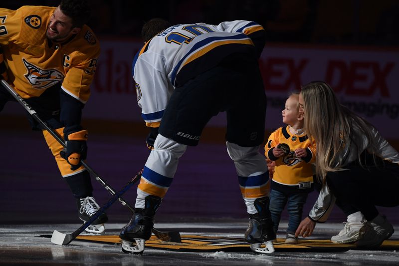 Apr 4, 2024; Nashville, Tennessee, USA; A hockey fights cancer ambassador holds the puck during the ceremonial puck drop with Nashville Predators defenseman Roman Josi (59) and St. Louis Blues center Brayden Schenn (10) before the game at Bridgestone Arena. Mandatory Credit: Christopher Hanewinckel-USA TODAY Sports